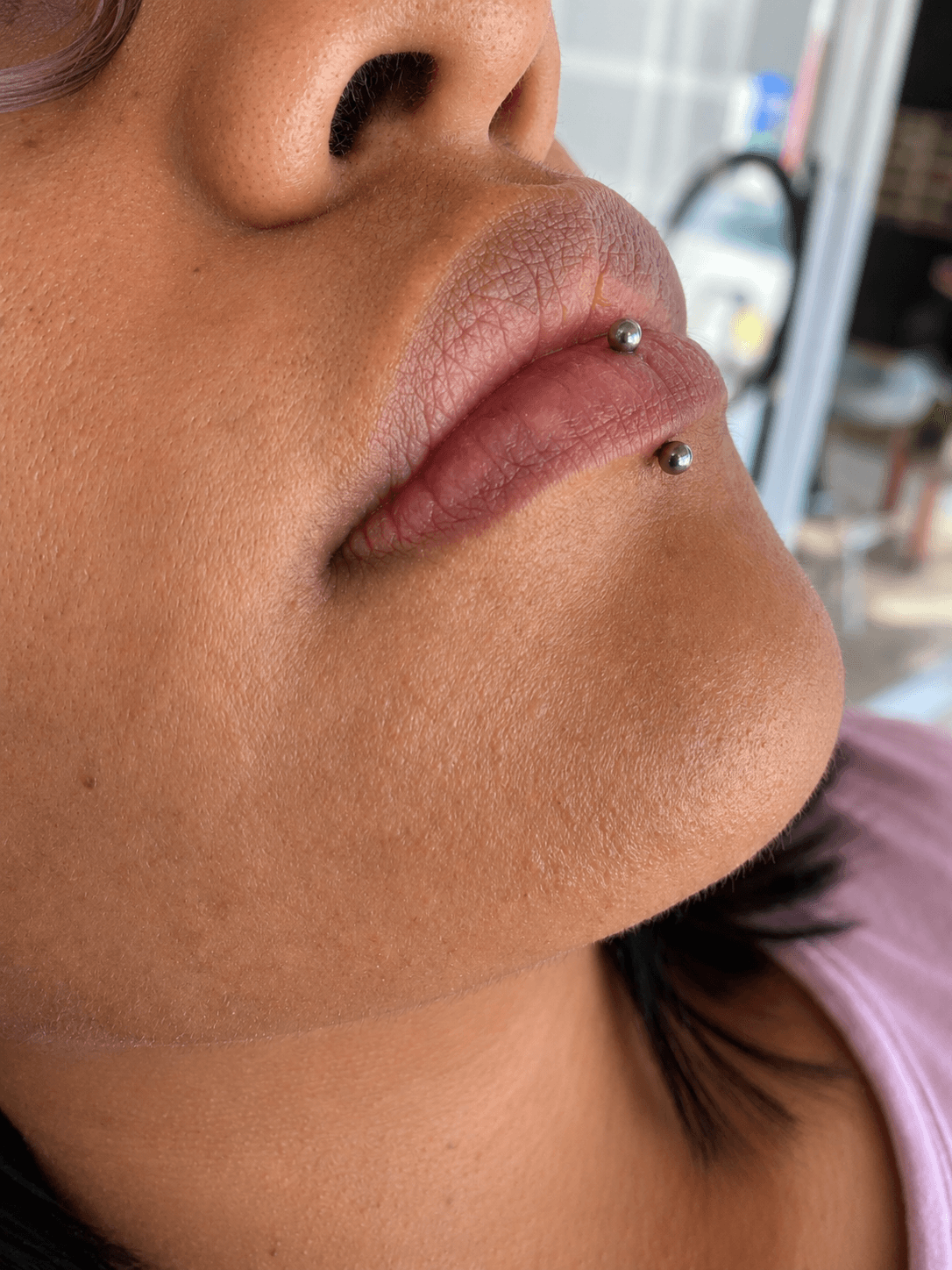 Piercing labret vertical con joyería plateada realizado por Mambas