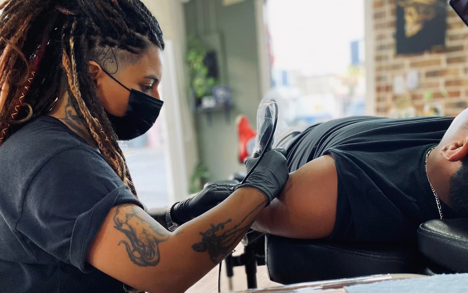 Artista de Mambas tatuando brazo en el estudio