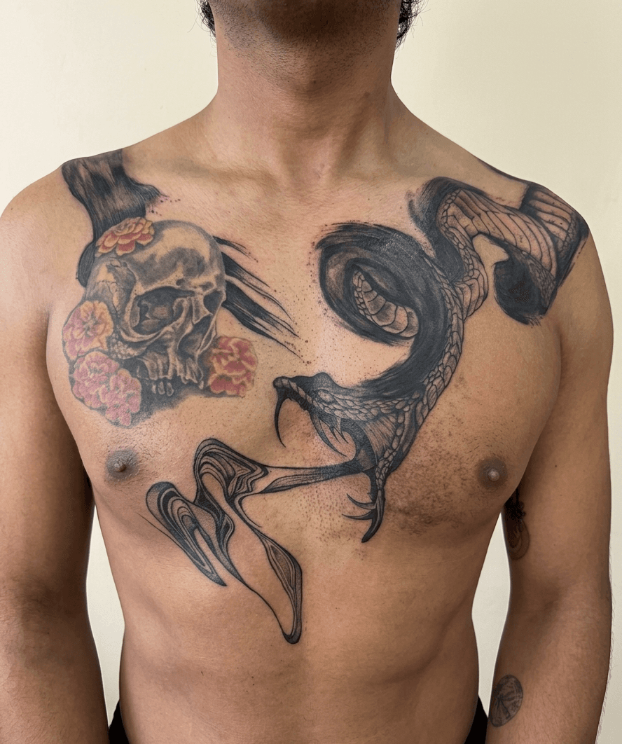 Tatuaje de pecho con serpiente y cráneo realizado por Mambas Tattoo