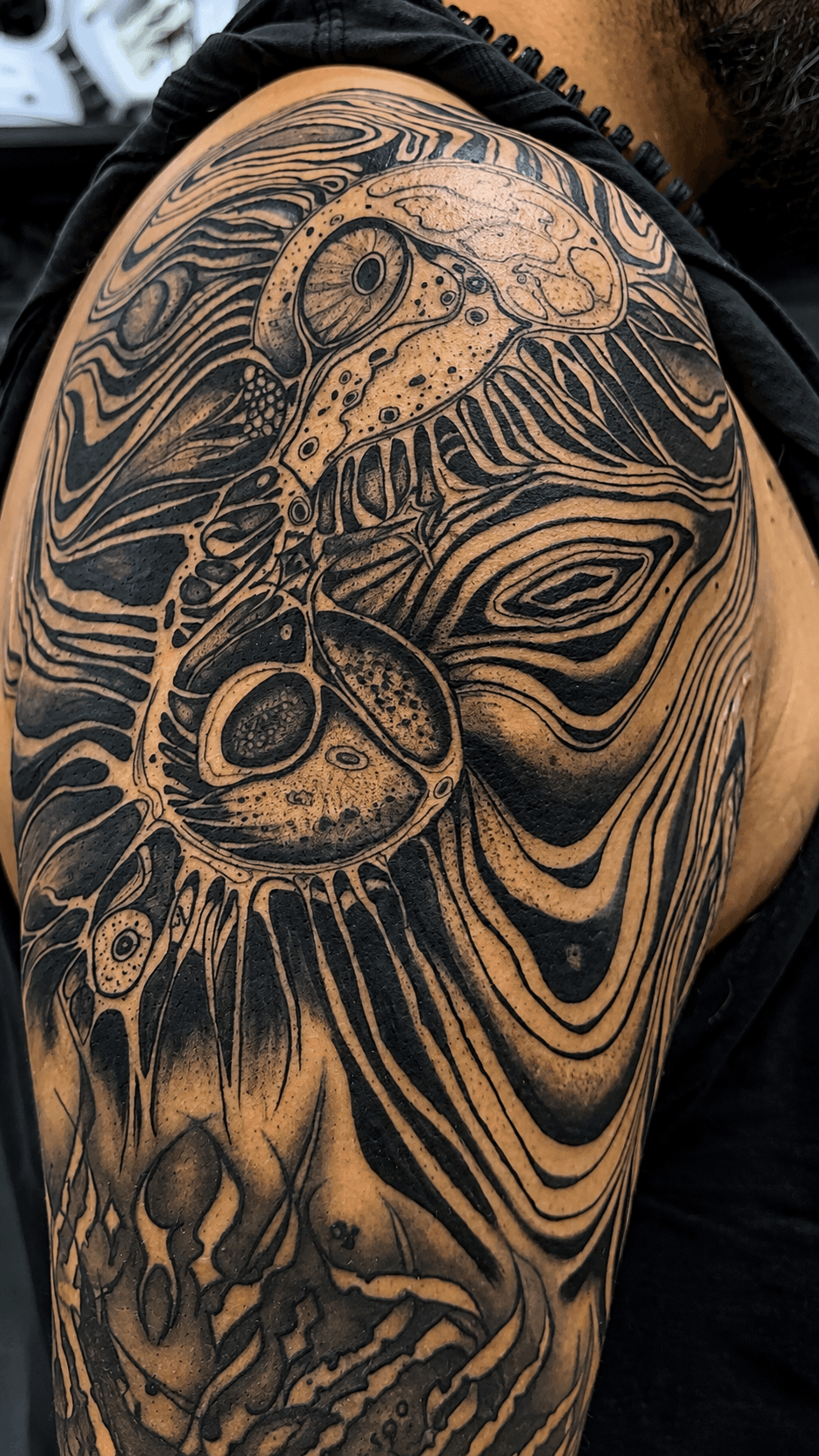 Tatuaje blackwork de hombro con diseño abstracto orgánico realizado por Mambas Tattoo
